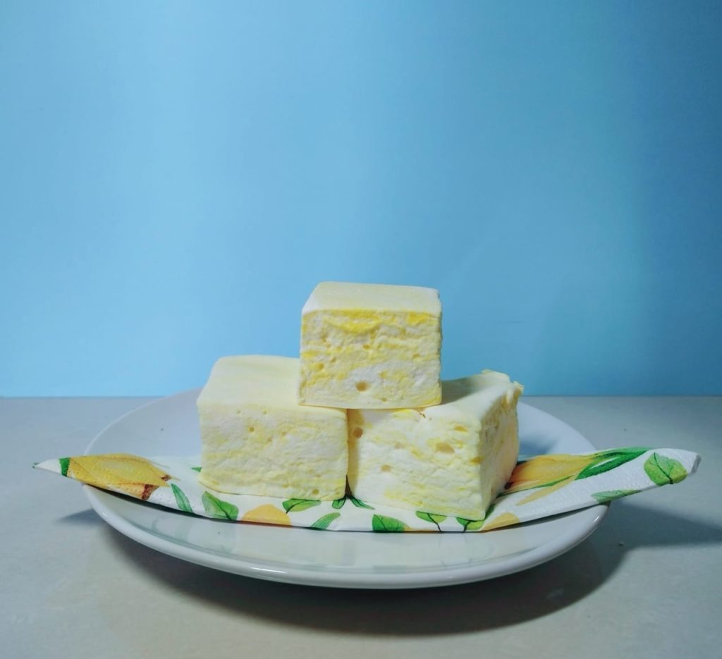Lemon marshmallows on a plate against a blue wall